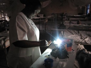A Nigerian nurse prepares injections by the light of her solar lamp.
